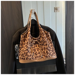 Detail of leopard print tote bag with brown leather handles and decorative front bow