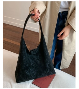 Detail shot of black matte hobo tote bag featuring wide shoulder strap and gold brand logo