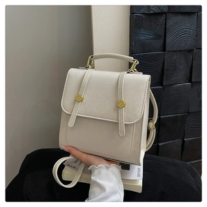Vue détaillée du sac à dos en cuir blanc cassé avec doubles sangles et boucles dorées