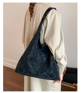 Detail of black slouchy hobo bag showing its vintage matte texture and wide shoulder strap