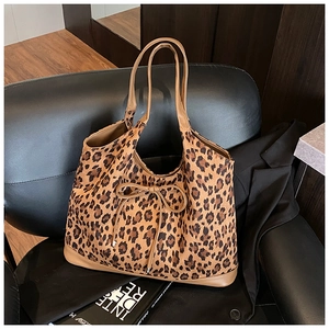 Detailed view of leopard print tote bag with bow accent on a stylish leather chair