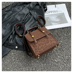 Détails de la texture léopard et des ferrures dorées sur le sac à dos carré marron foncé