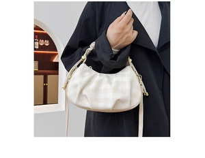 Detail of cream checkered cloud bag showing ruffled texture and golden hardware