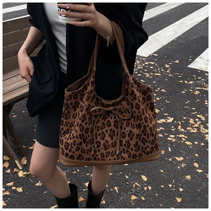 Outdoor street style shot of a leopard print tote bag with a bow and leather trim