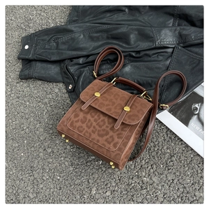 Vue à plat d'un sac à main léopard avec boucles dorées sur une veste en cuir et gravier