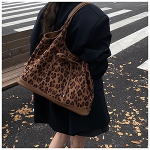 Close-up of leopard print tote bag with leather bow detail on model in urban street setting