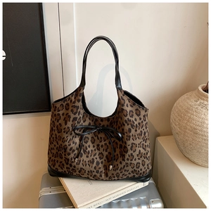 Detail of leopard print tote bag with black bow tie on silver suitcase background