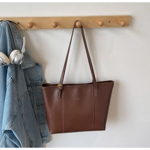Détail du grand sac cabas marron foncé avec texte doré et cuir synthétique de qualité