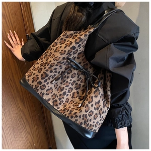 Detail of leopard print tote bag featuring a black bow and contrast leather shoulder strap