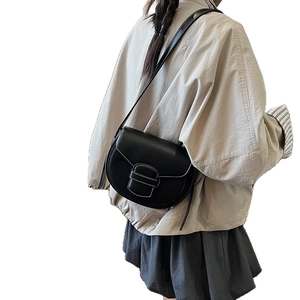 Minimalist black leather saddle bag with white contrast stitching and long shoulder strap