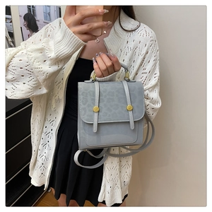 Détail d'un sac bandoulière bleu clair avec rabat léopard et boucles métalliques dorées