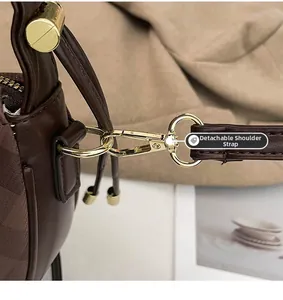 Macro view of detachable strap with gold metallic buckle on dark brown leather bag