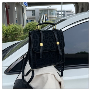 Détail du sac à dos léopard noir avec poignée en métal doré et lanières en cuir