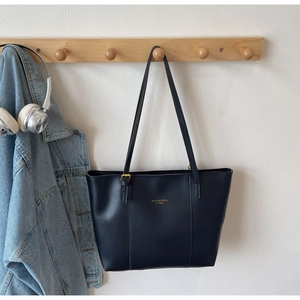 Détail du sac cabas noir avec boucles dorées et texte de logo imprimé doré
