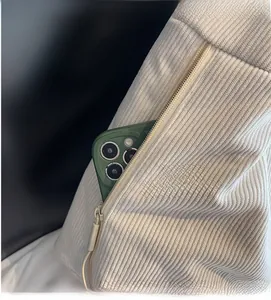 Détail d'un sac à bandoulière en velours beige montrant une poche latérale zippée