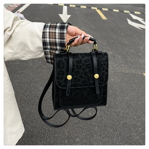 Gros plan sur la texture léopard du sac à dos carré noir mat avec ferrures dorées