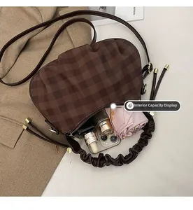 Spacious interior of a brown checkered cloud bag showing phone, cosmetics, and umbrella