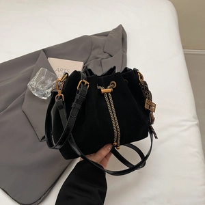 Retro black matte bucket bag with gold chain drawstring and abacus charm on white bedding