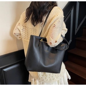 Vue latérale d'un grand sac cabas en cuir noir avec lettrage doré dans un cadre chic