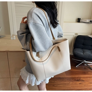 Détail d'un grand sac fourre-tout blanc crème avec anses marron porté par un mannequin
