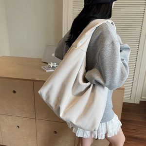 Détail d'un sac hobo en velours côtelé crème avec fermeture éclair et texture rayée