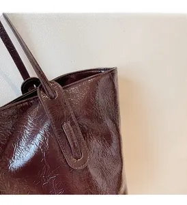 Detail view of burgundy tote bag showing meticulous stitching and glossy wrinkled leather