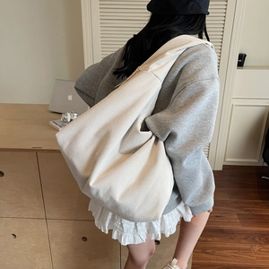 Détail de la texture en velours côtelé et forme de croissant du sac crème spacieux