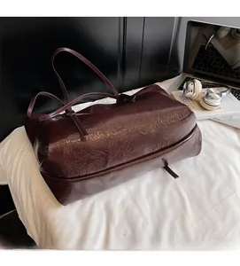 Detail of dark red tote bag with glossy oil-waxed leather texture and long shoulder straps