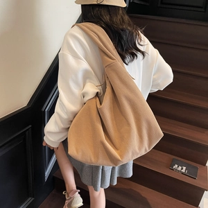 Détail de la texture en velours côtelé kaki doux et de la large bandoulière du sac hobo