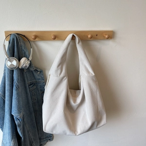 Détail du sac hobo en velours côtelé crème avec large bandoulière sur un cintre