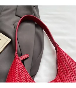 Dettaglio della borsa tote rossa intrecciata con tracolla in pelle liscia e chiusura lampo