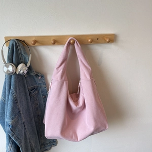 Sac hobo en velours côtelé rose suspendu avec une veste en jean dans un décor douillet
