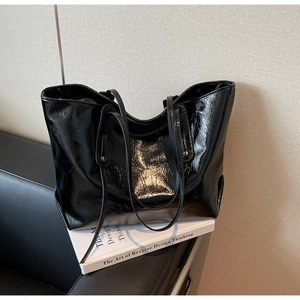 Macro detail of high-shine black patent leather tote bag with metallic rivet accents
