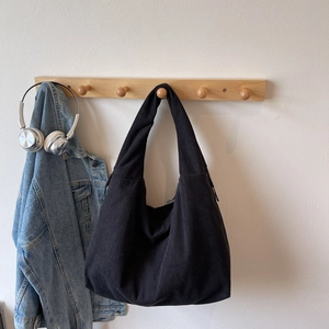 Détail d'un sac hobo en velours côtelé noir avec texture rayée sur un crochet
