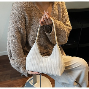 Vue détaillée du sac porté épaule blanc tressé, design croissant élégant et texture chic.