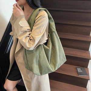 Détail de la texture en velours côtelé vert du sac porté avec un trench-coat kaki