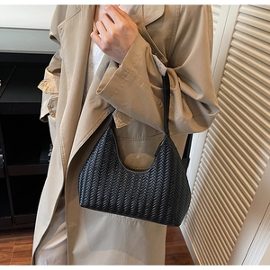 Sac porté épaule noir en cuir tressé avec une silhouette élégante de croissant et bandoulière.