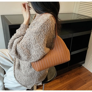 Vue détaillée d'un élégant sac hobo tressé marron porté avec un pull en maille douillet.