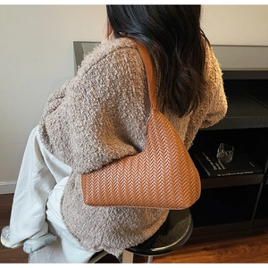 Dettaglio della borsa hobo intrecciata color caramello che mostra texture e artigianalità