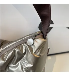 Détail de la fermeture éclair en métal et du tissu matelassé sur le sac champagne