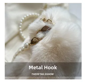 Detail of white plush shoulder bag featuring gold metal hooks and pearl chain strap accents