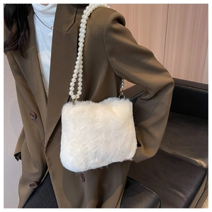 Detailed view of white faux fur shoulder bag featuring large pearl chain strap on model