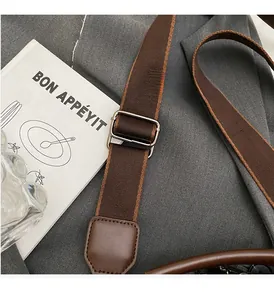 Close-up of dark brown canvas shoulder strap with polished silver metal adjustment buckle