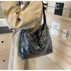 Détail d'un sac à bandoulière matelassé noir au fini brillant avec boucles métalliques