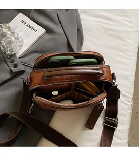 Detail view of brown pebbled leather crossbody bag with multiple zipper compartments