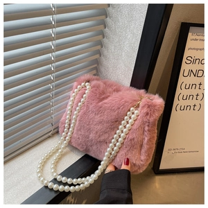 Detail of pink faux fur shoulder bag with thick white pearl chain strap in soft sunlight