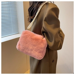 Detail of pink plush faux fur bag with large white pearl shoulder strap on brown wool coat