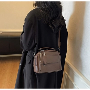 Detail of dark brown pebble leather handbag with silver rivets and long zipper puller