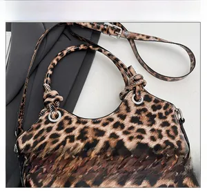 Detail of leopard print bucket bag featuring knotted handles and silver ring hardware