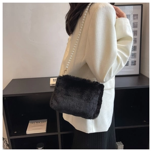 Close-up of black plush shoulder bag featuring a decorative large pearl chain strap